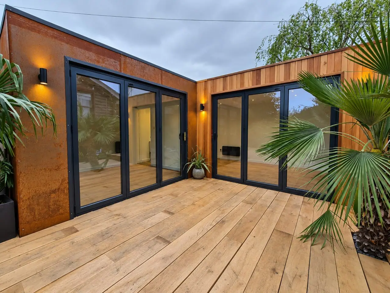 Connected timber garden buildings with deck and planted setting